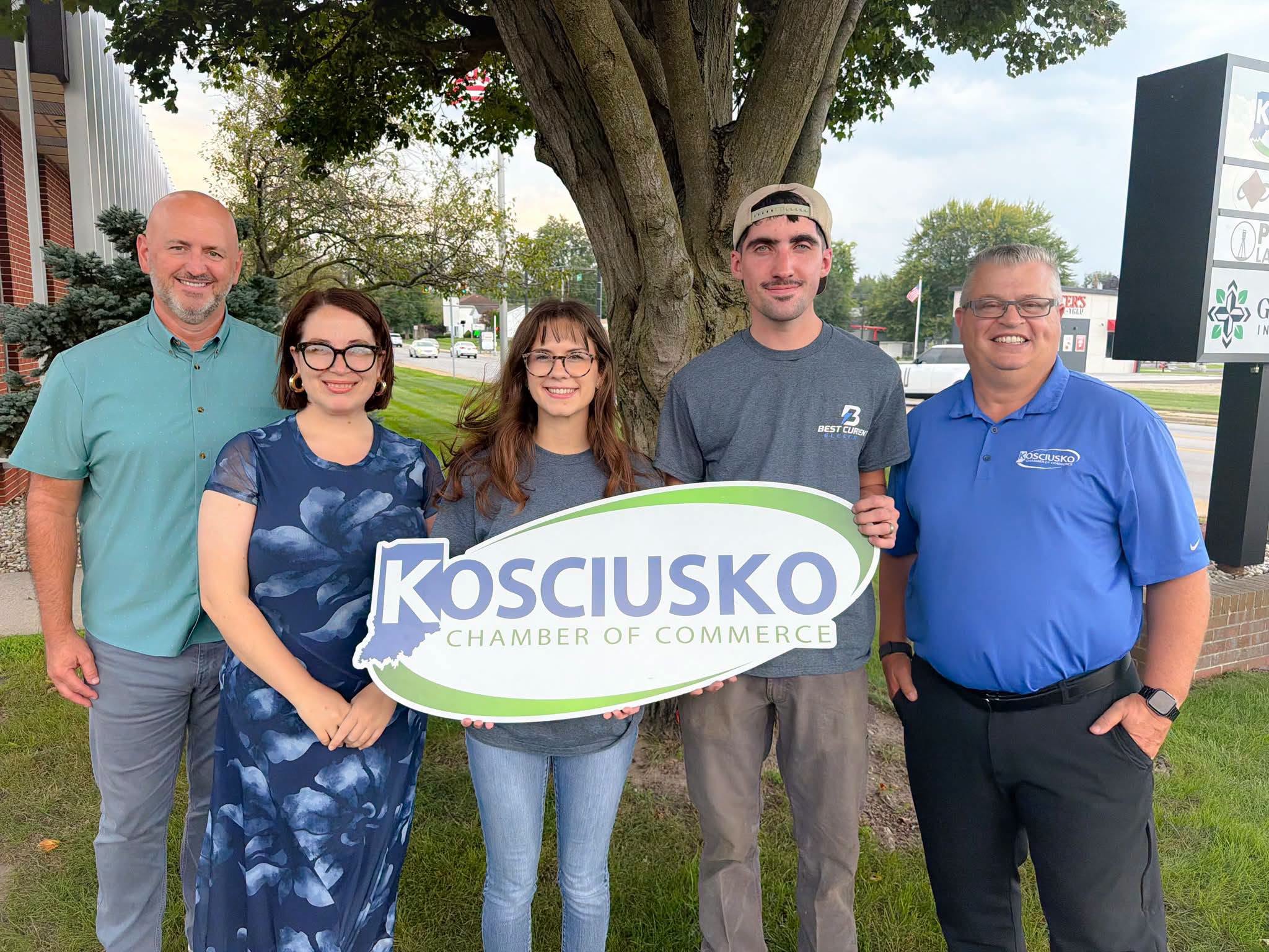 Best Current Electric pictured with Kosciusko Chamber of Commerce representatives, holding the Chamber sign.